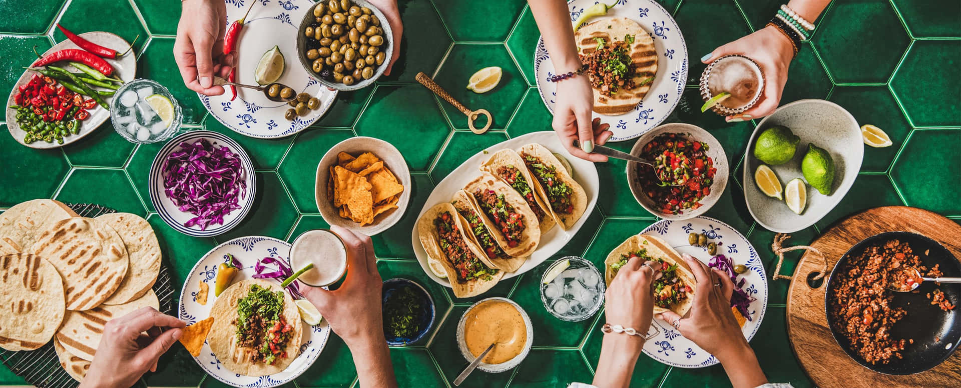 Ungrupo De Personas Comiendo Comida En Una Mesa Con Azulejos Verdes.
