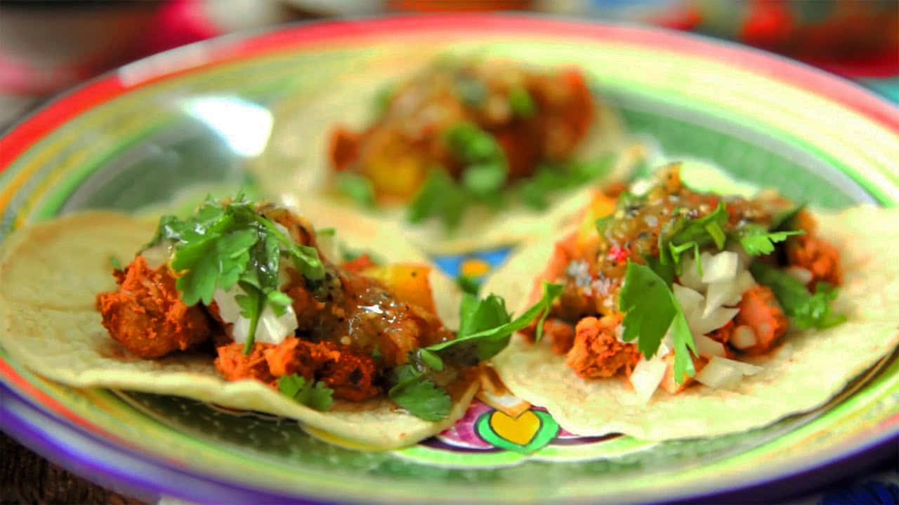 Three Tacos On A Plate With Cilantro And Onions