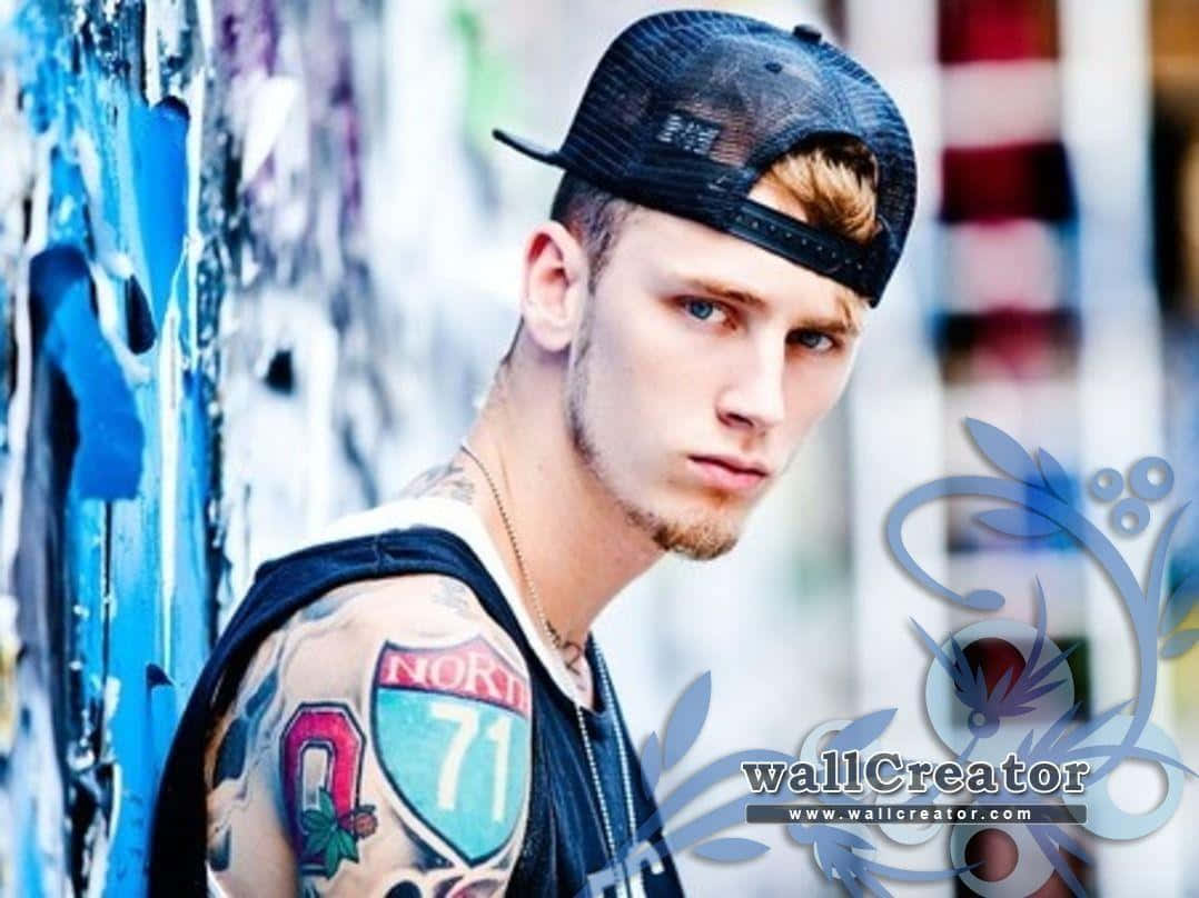 Download A Young Man With Tattoos Leaning Against A Wall Wallpaper.