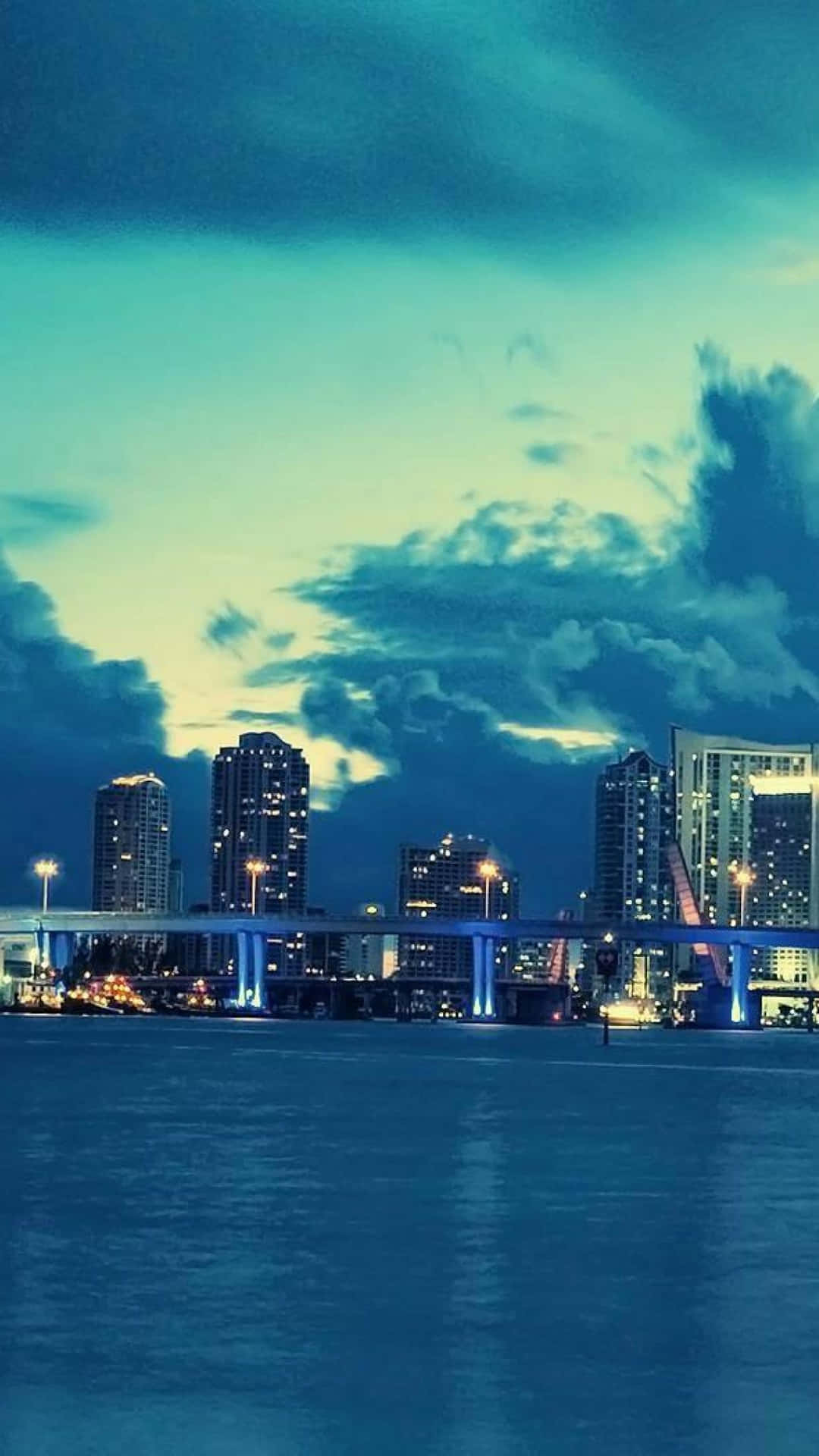 A City Skyline With Clouds Over The Water Wallpaper