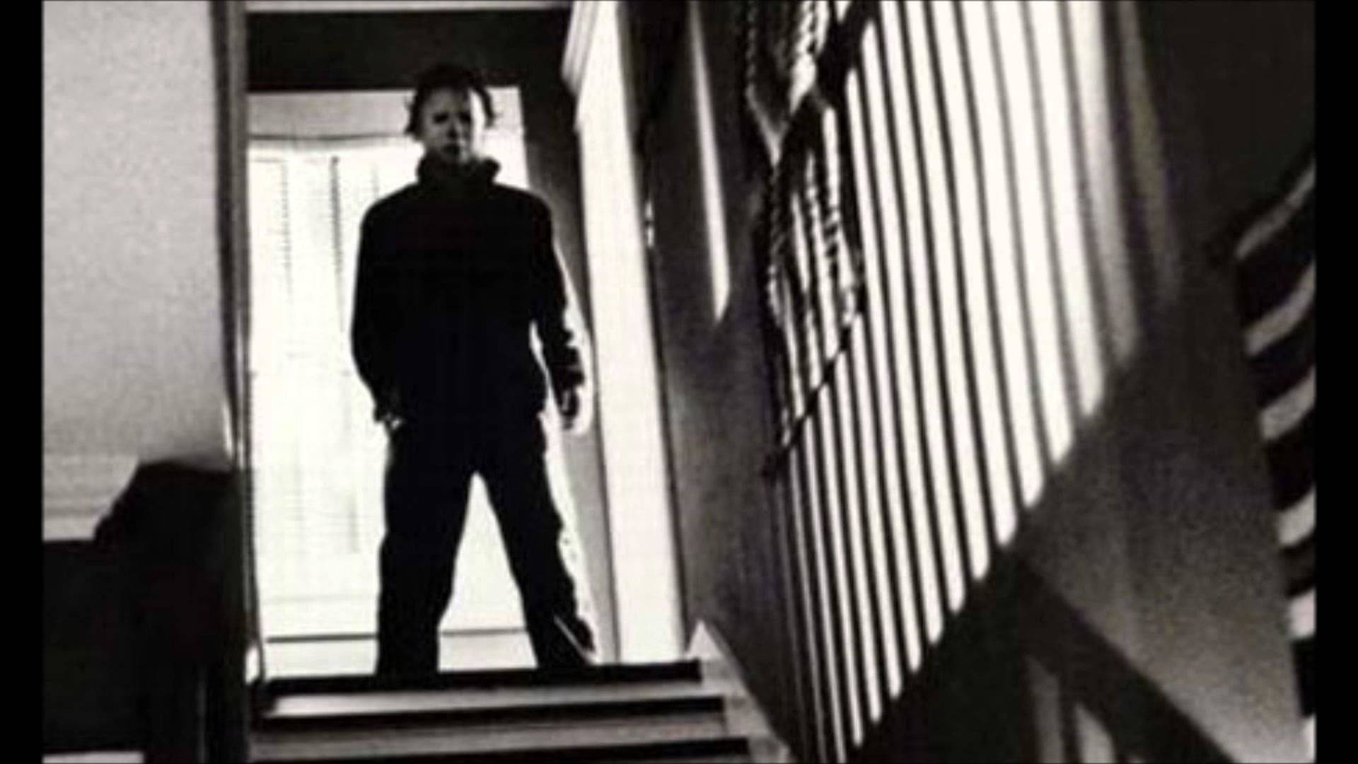 Michael Myers menacingly appearing at the top of the stairs in a suspenseful scene Wallpaper