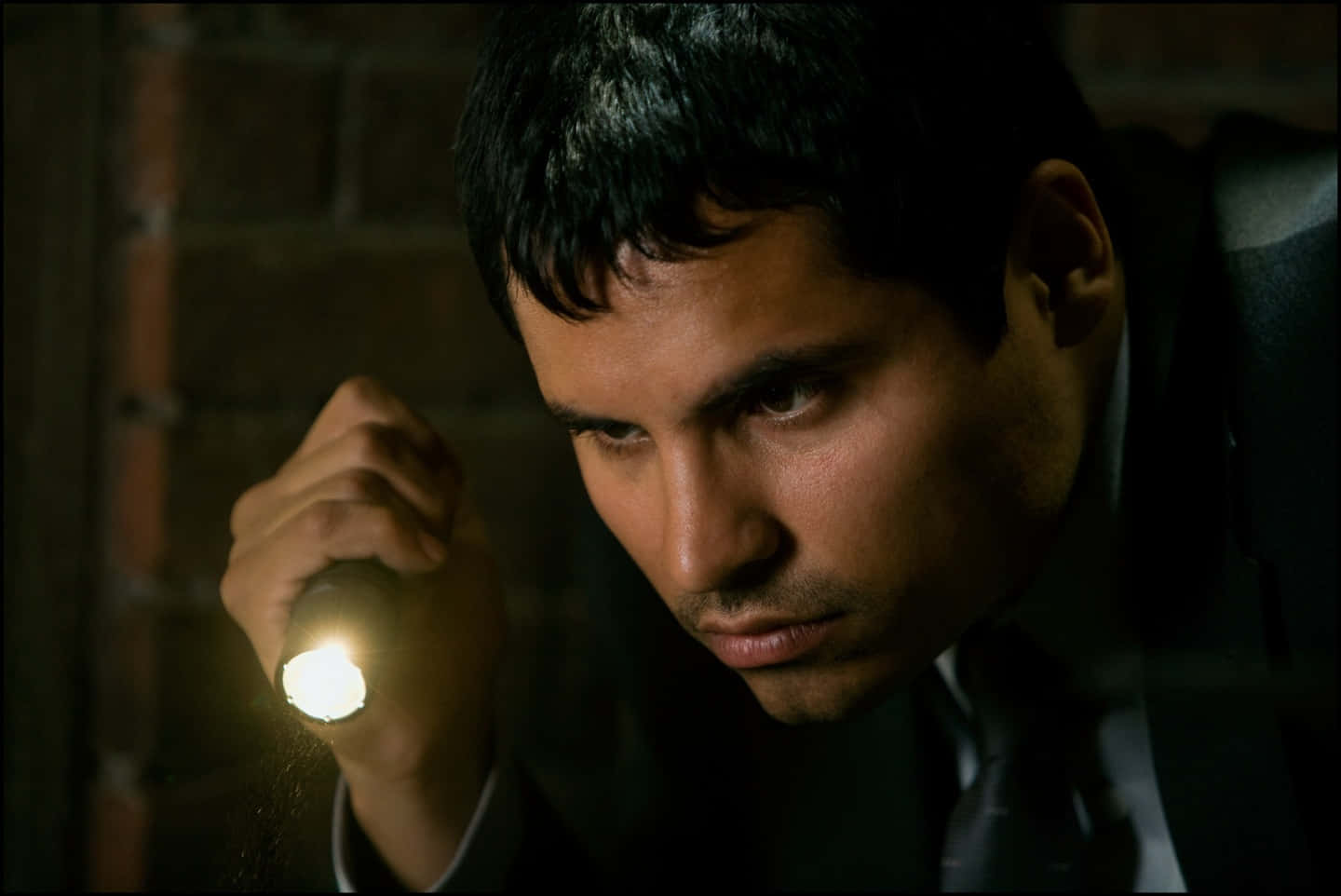 Actor Michael Peña sporting a tweed jacket while lounging on a patio chair" Wallpaper