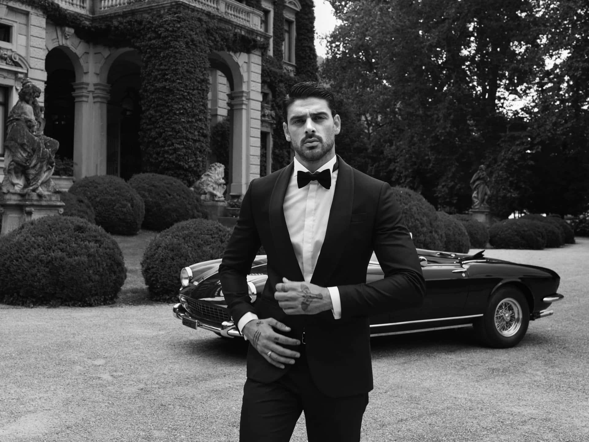 A Man In A Tuxedo Standing Next To A Car