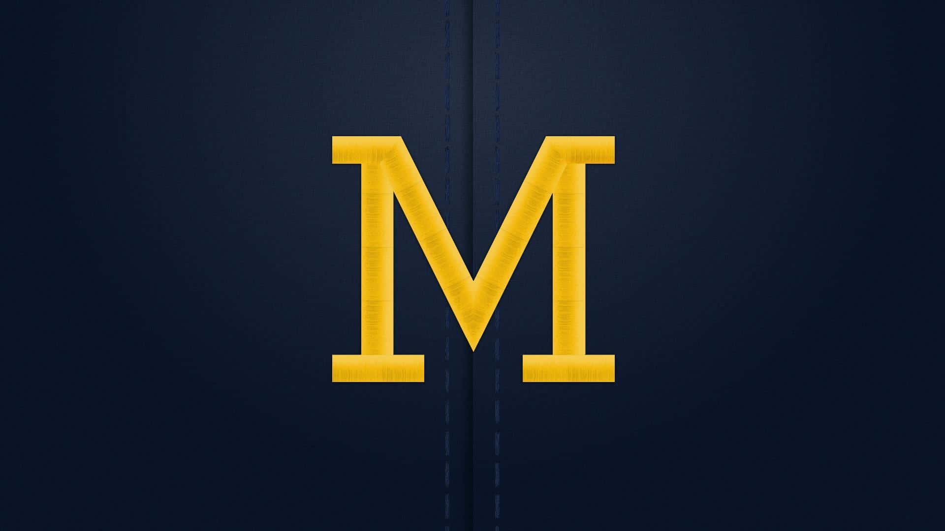 Michigan Wolverines logo on a football field Wallpaper