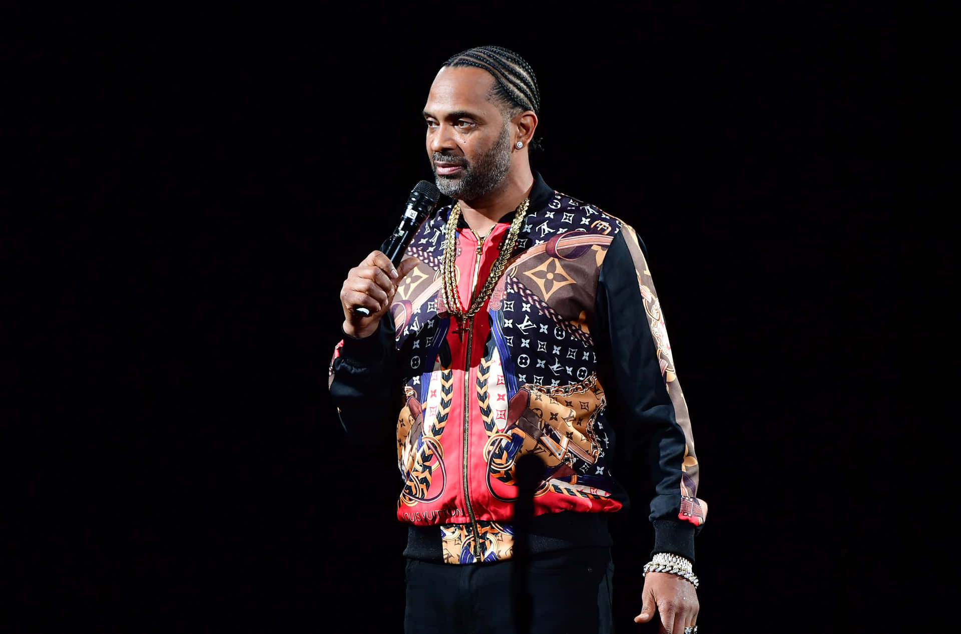 Mike Epps strikes a thoughtful pose against a textured grey wall backdrop. Wallpaper