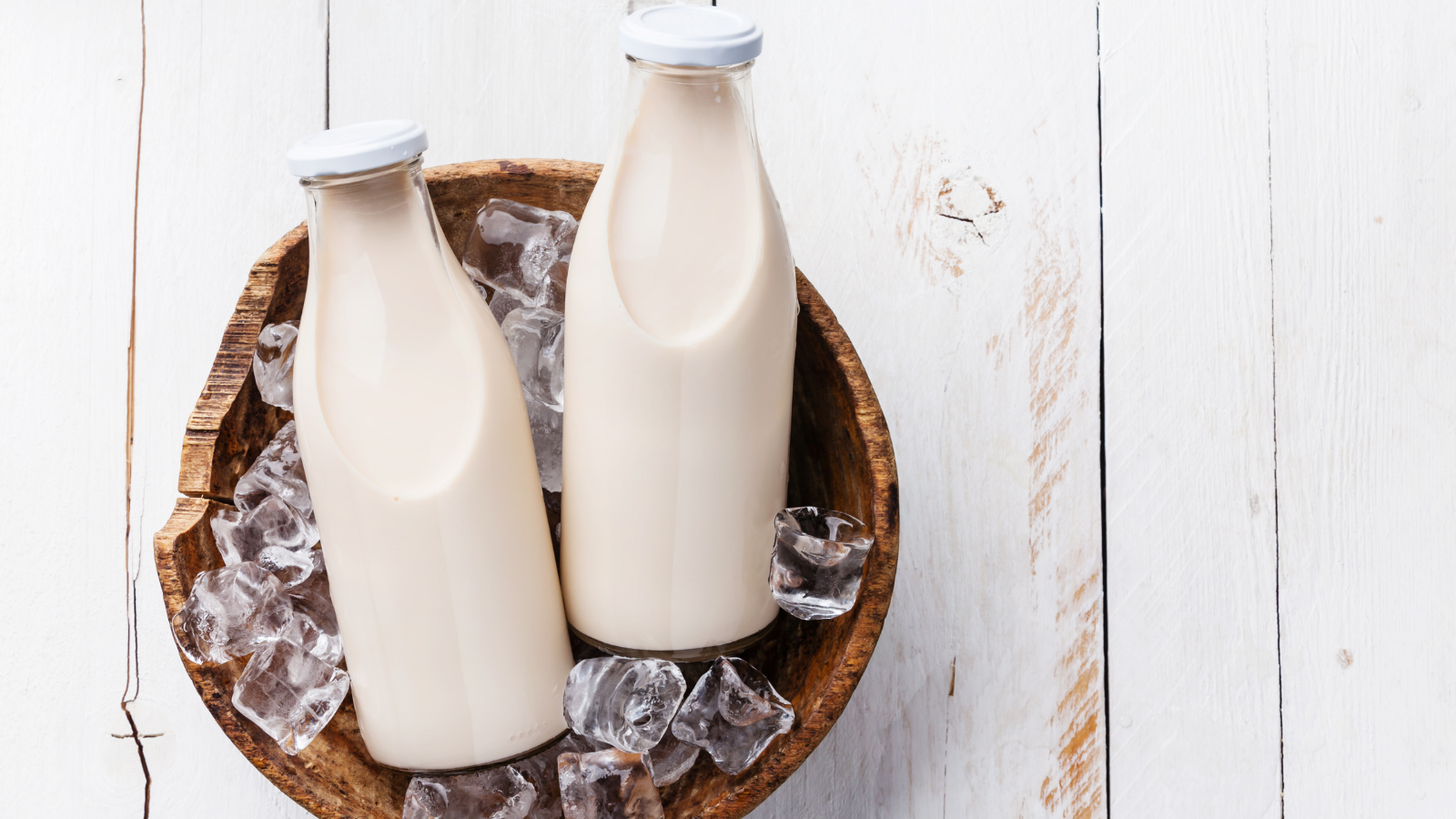 Two Bottles Of Milk In A Wooden Bowl