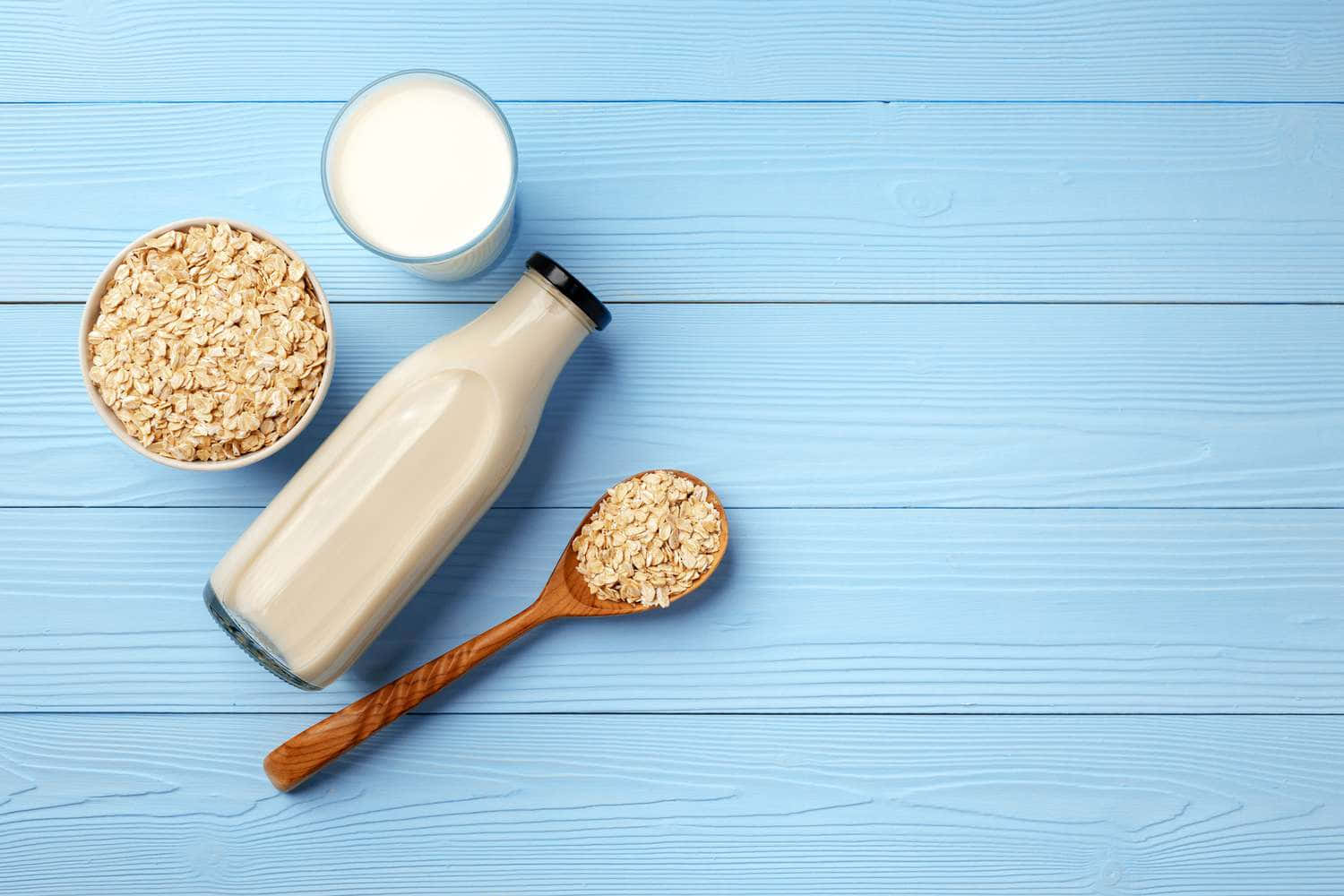 Milk, Oats And Spoons On A Blue Wooden Table