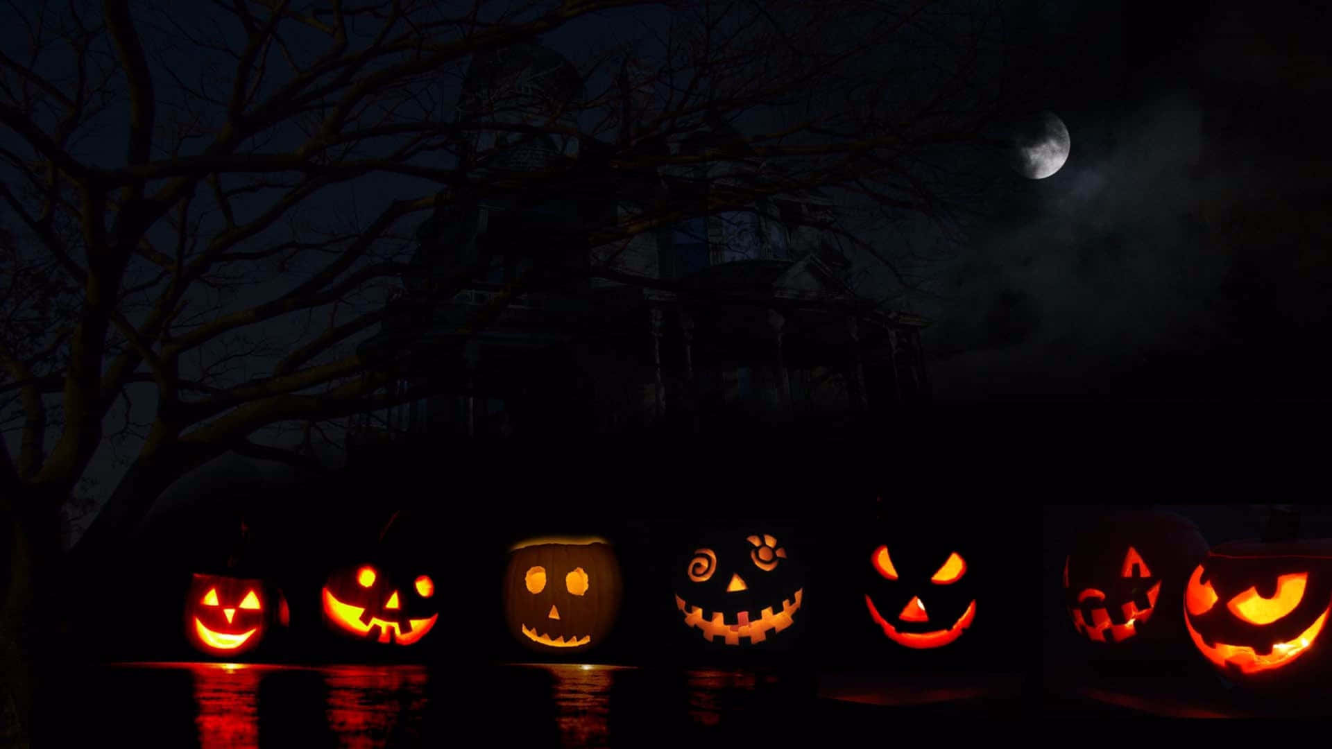 A Group Of Pumpkins With Faces Lit Up Wallpaper