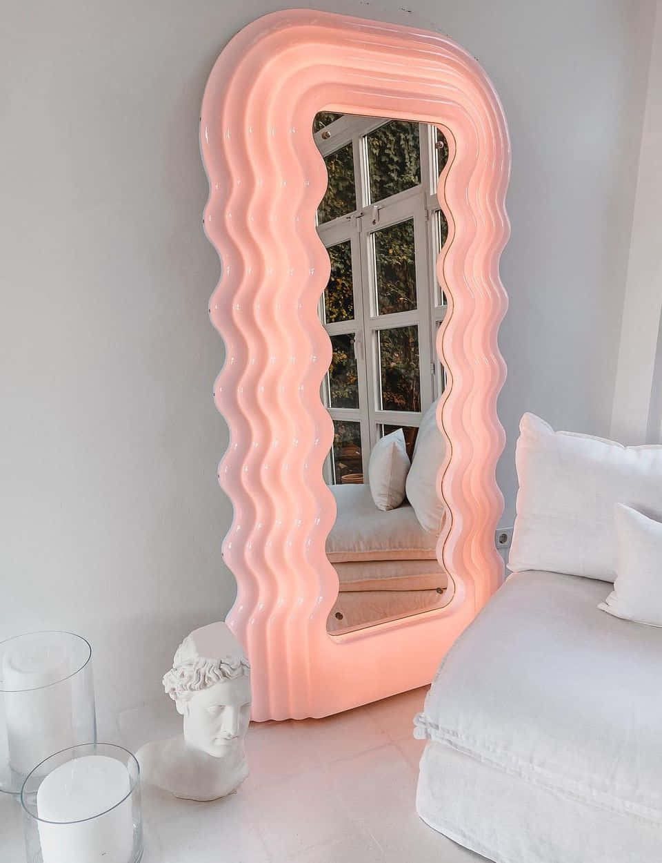 A Pink Mirror In A Room With White Furniture
