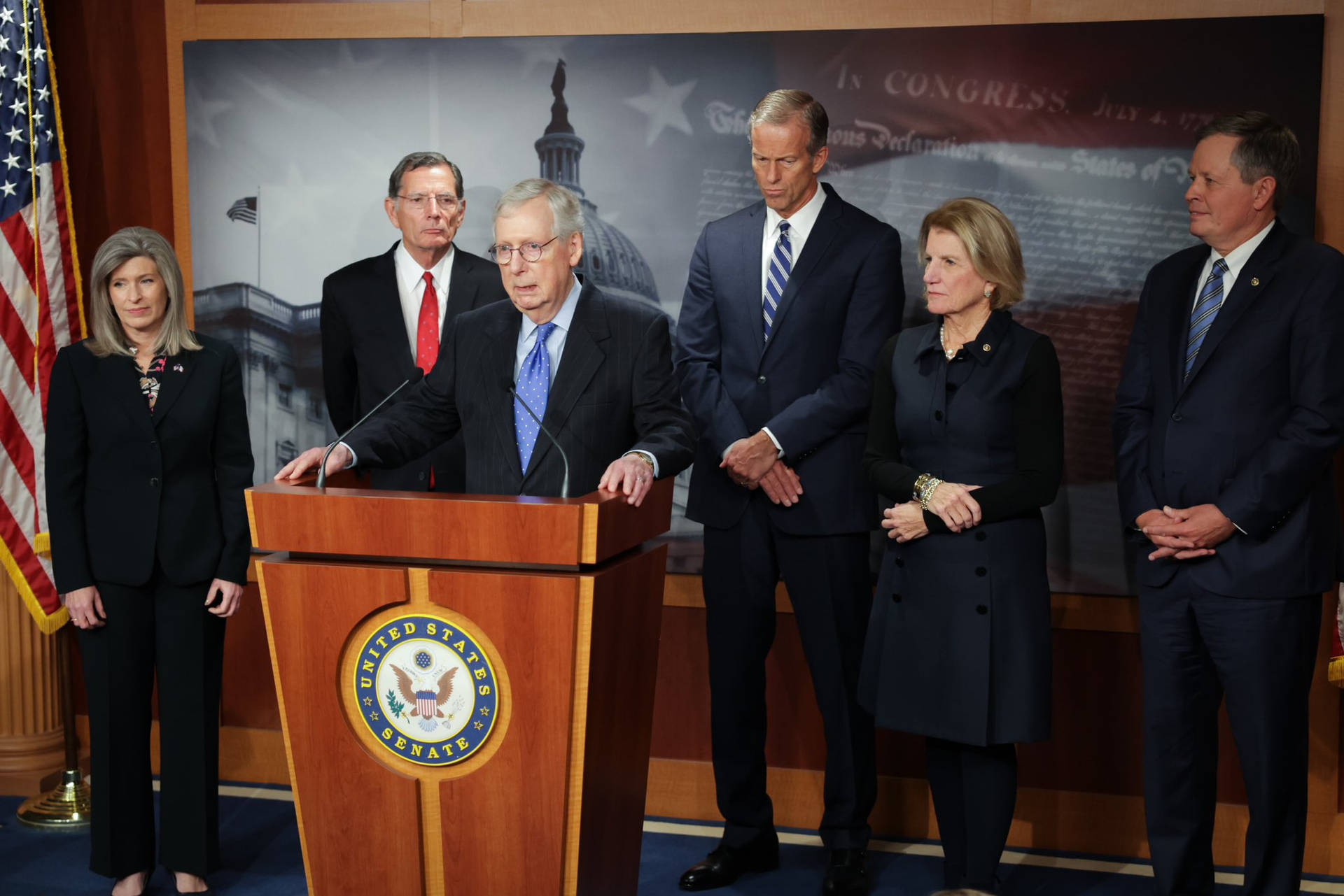 Mitch McConnell critiquing policies during a news conference Wallpaper