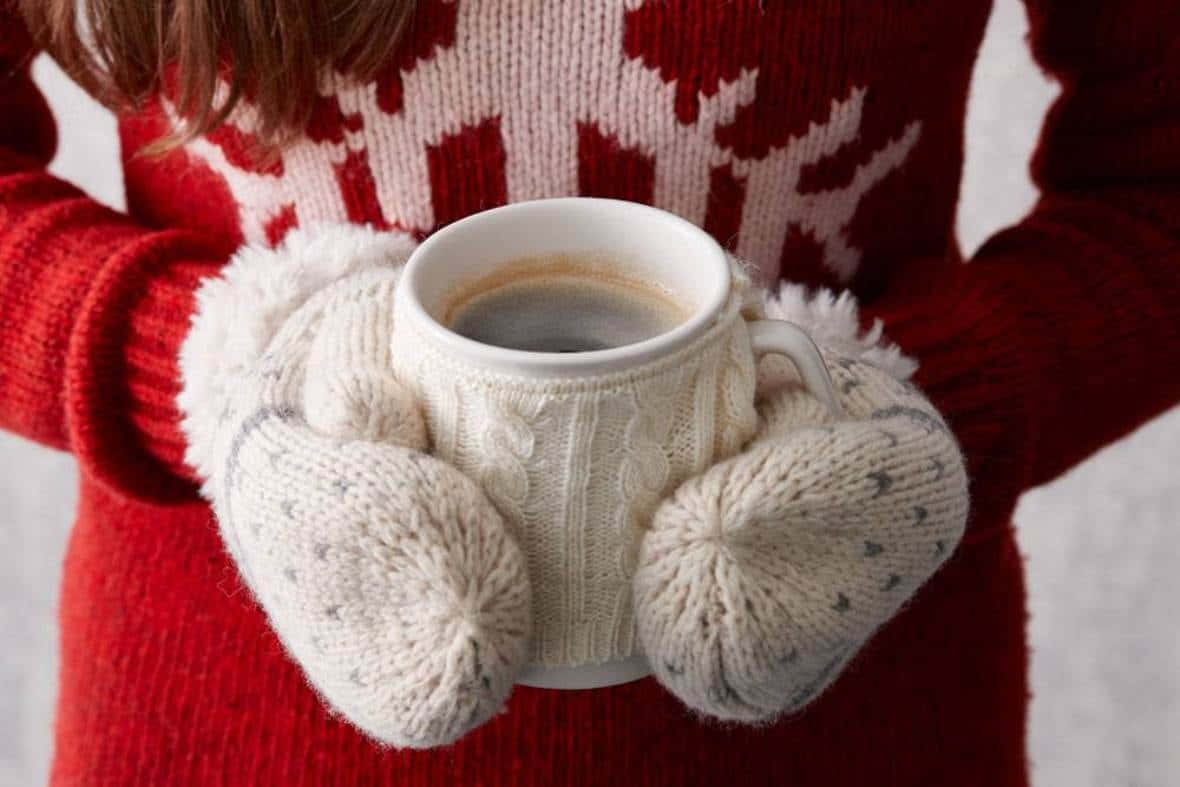 Cozy knitted mittens hanging in a winter setup. Wallpaper