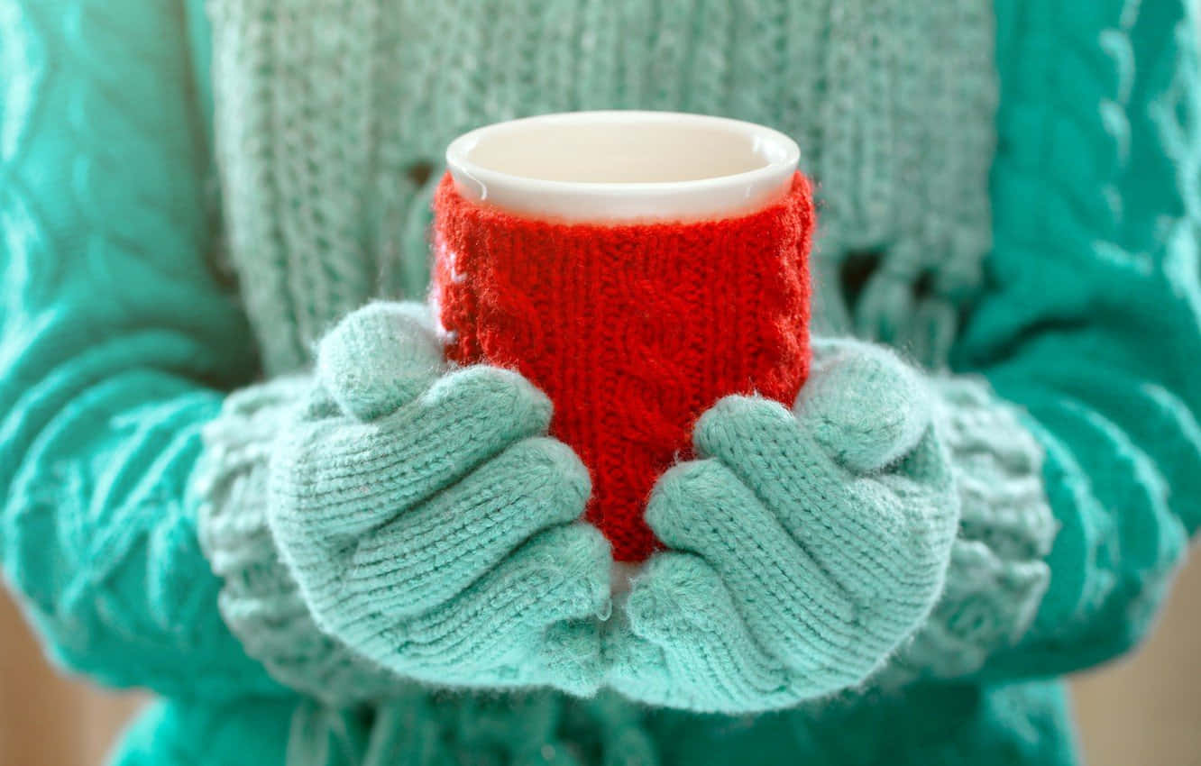 A pair of cozy knitted mittens on a wooden surface. Wallpaper
