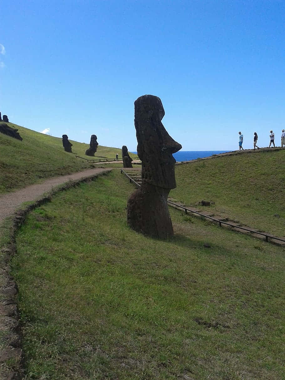 Figurer Moai med turister vinker på Komodo øen Wallpaper