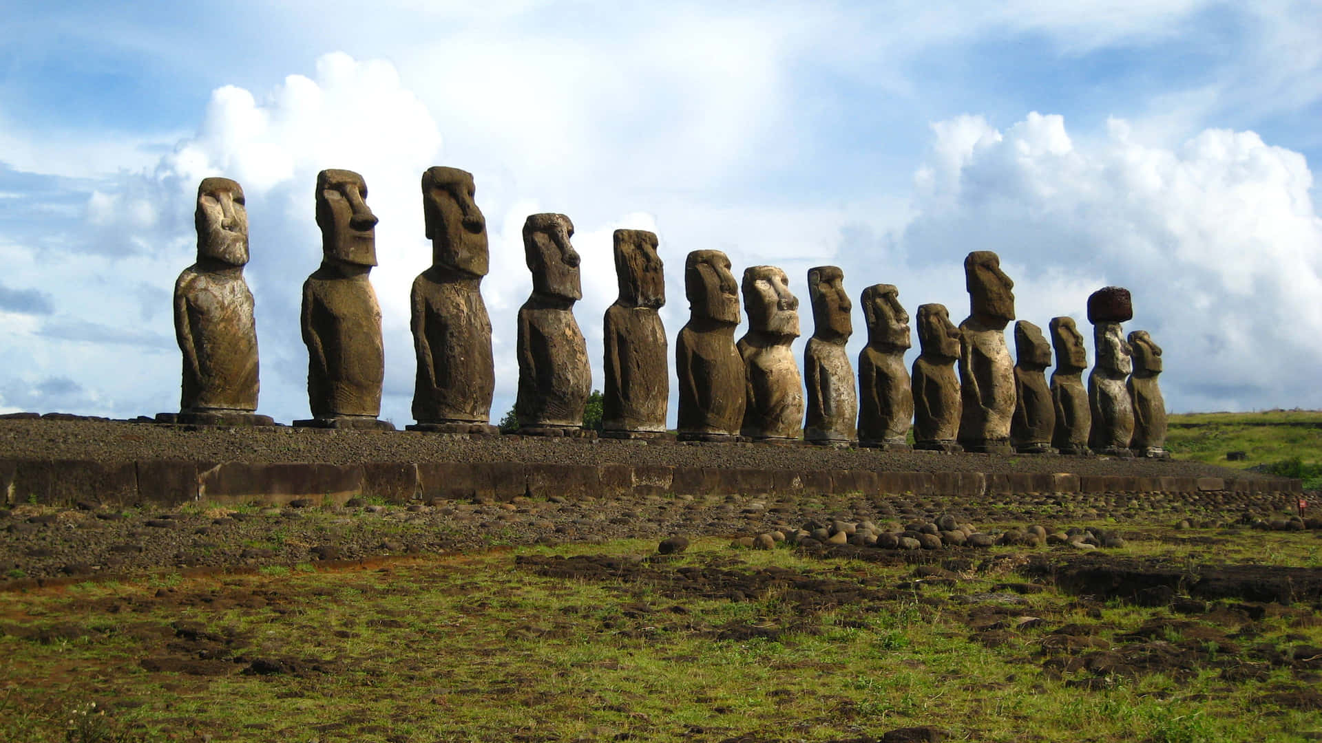 Moai skulpturer stille op langs en gammel væg Wallpaper