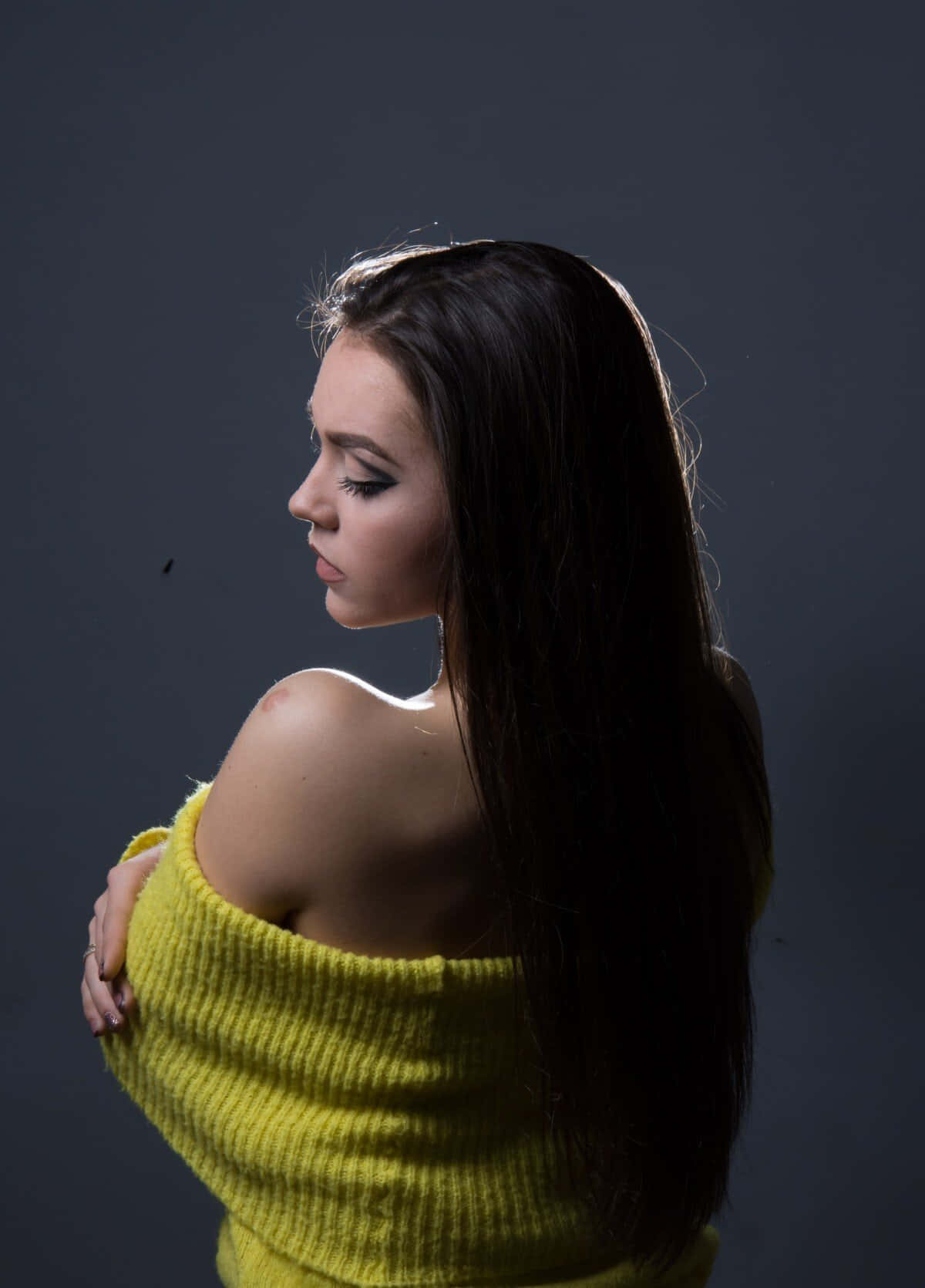 A Woman In A Yellow Sweater Posing On A Grey Background