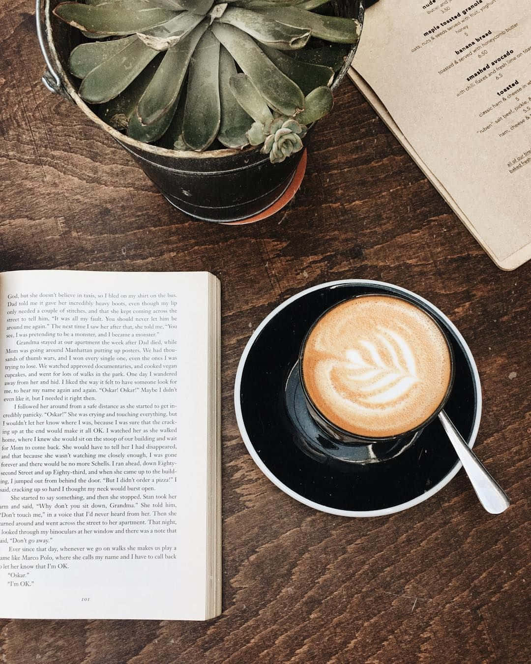 En bog, kaffe og en plante på et bord Wallpaper