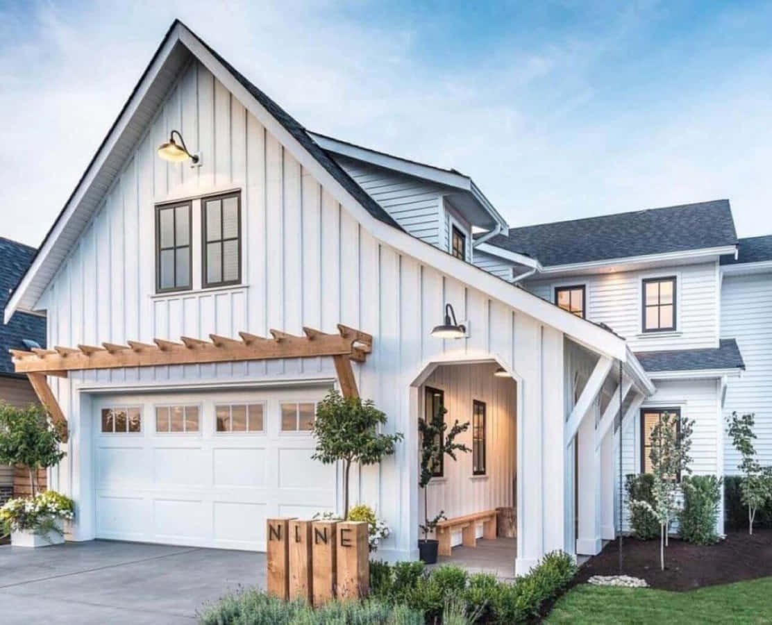 A White Farmhouse With A Garage And Driveway