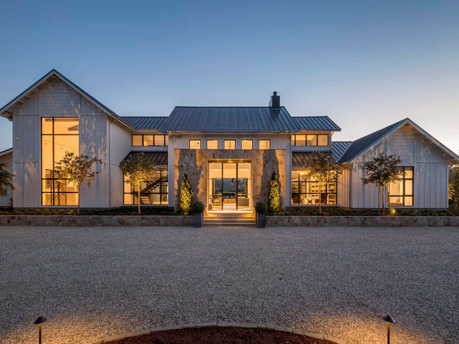 A Modern Farmhouse With A Large Driveway And Lighting