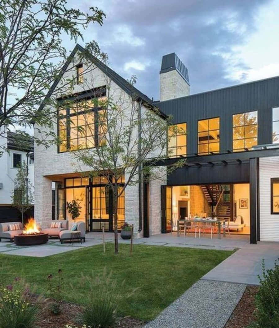 A Modern Home With A Large Yard And Fire Pit