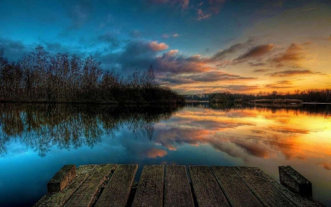 A Dock With A Sunset Over The Water Wallpaper