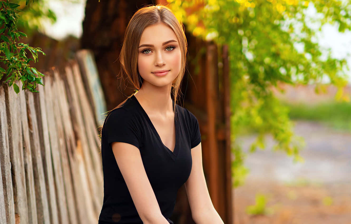 A Beautiful Woman Sitting On A Wooden Bench Wallpaper