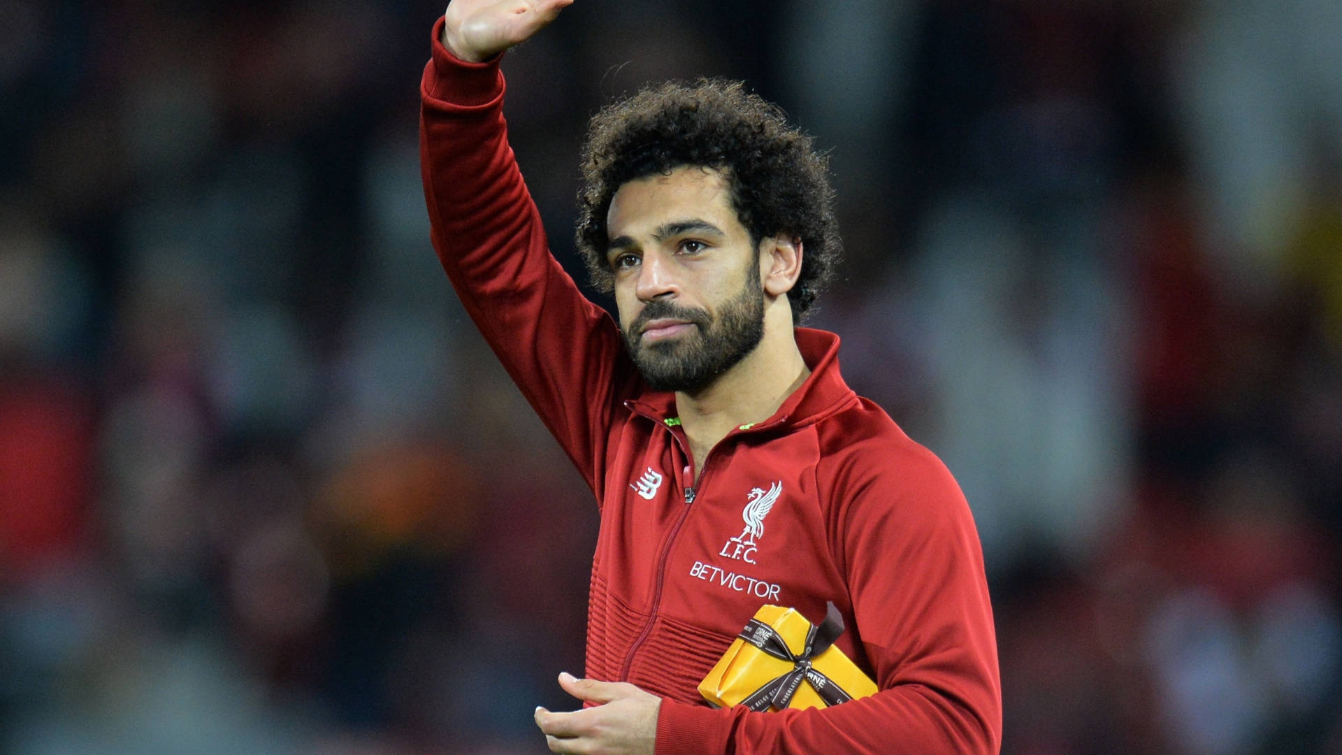 Mohamed Salah Waving With A Gift Wallpaper