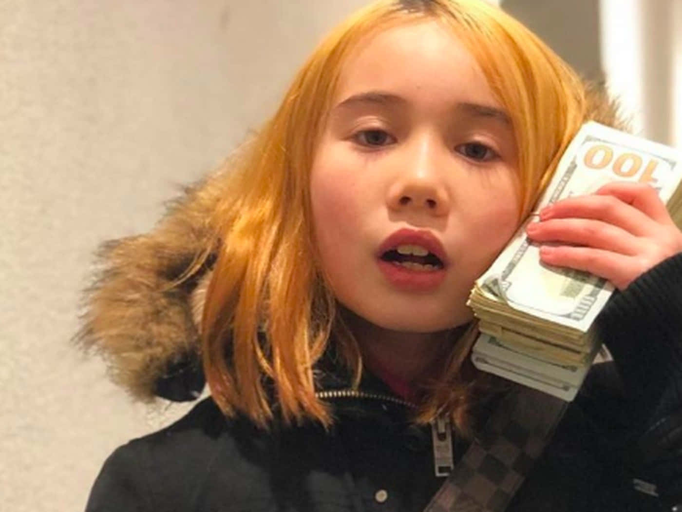 A Girl With Orange Hair Holding Up Money