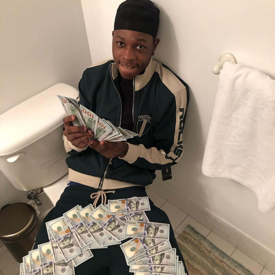 A Man Sitting On The Toilet Holding Money