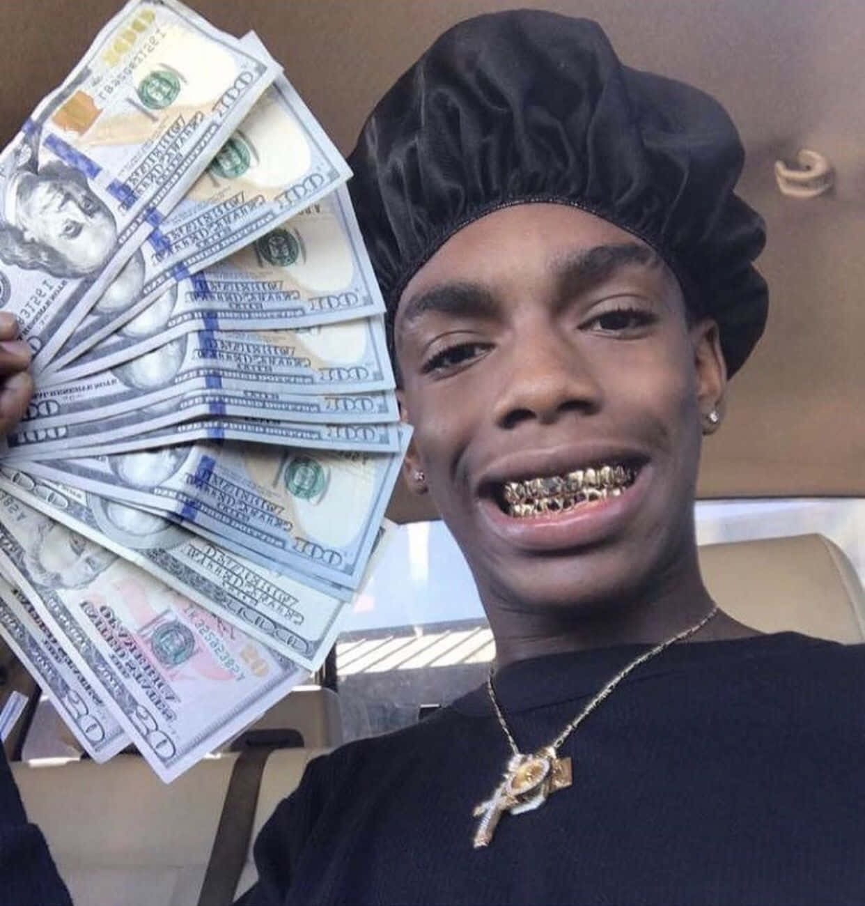 A Man Holding Up A Stack Of Money