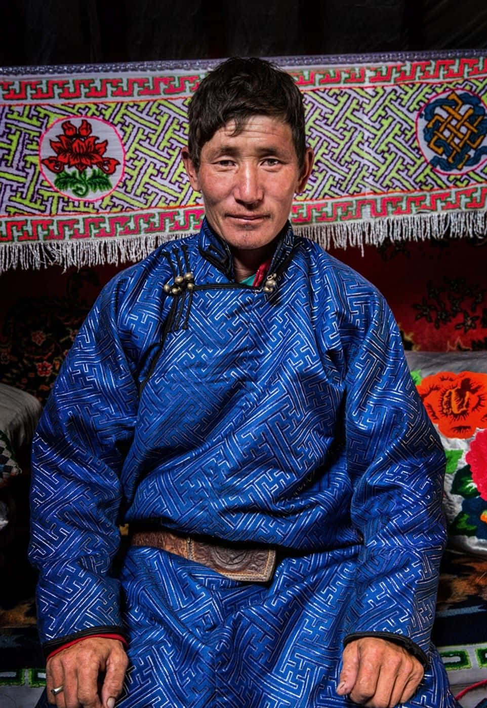 A Man In Traditional Clothing Sitting On A Rug