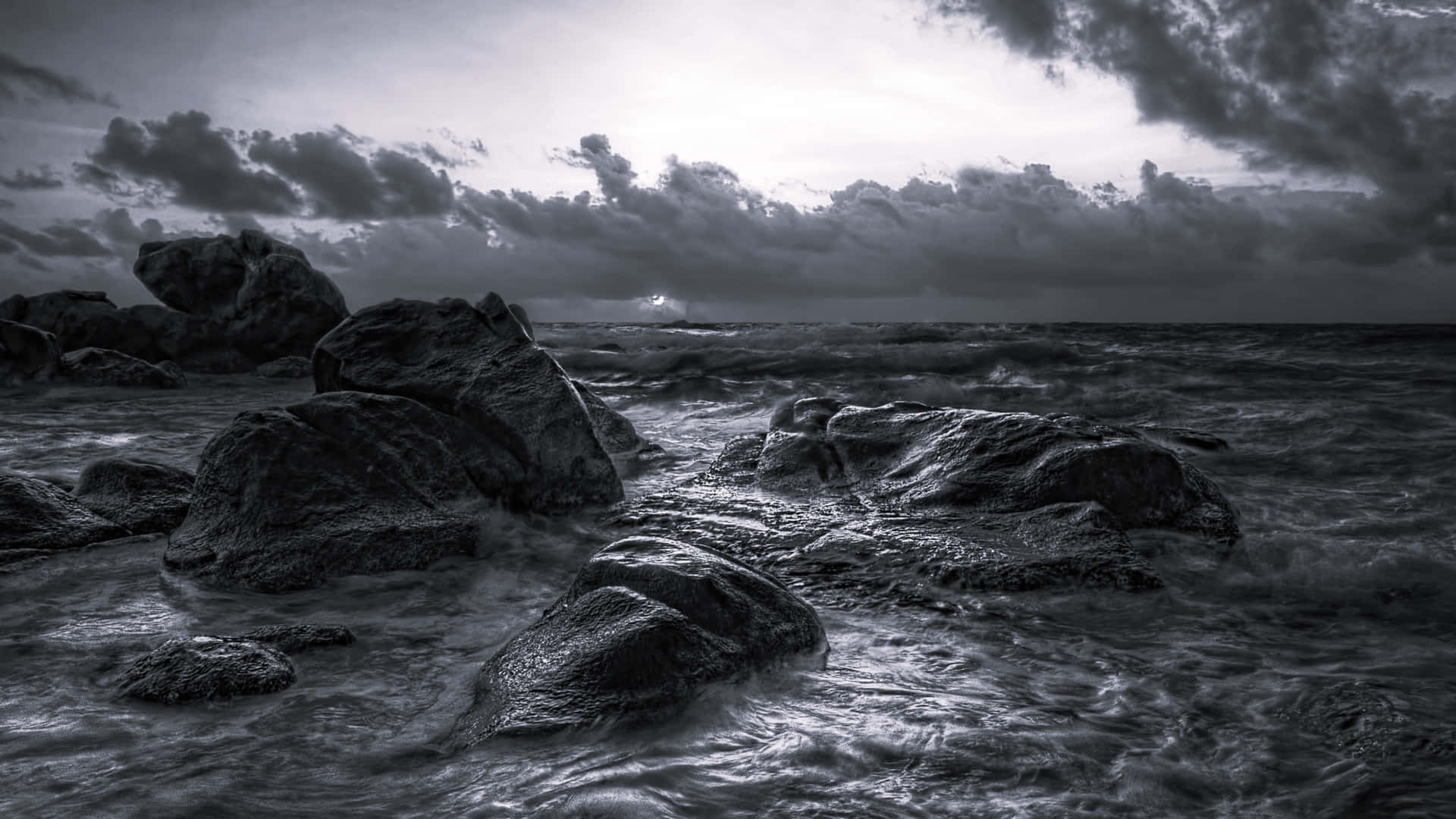 Monochroom_ Oceaan_ Zonsondergang_ Rotsen Achtergrond