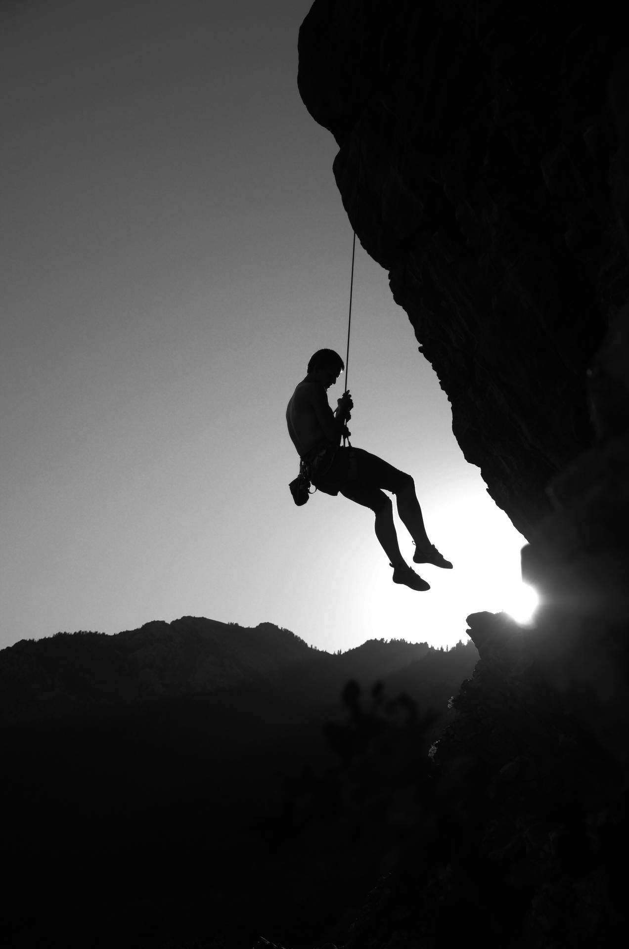 Monochrome Photo Of Man Rock Climbing Wallpaper