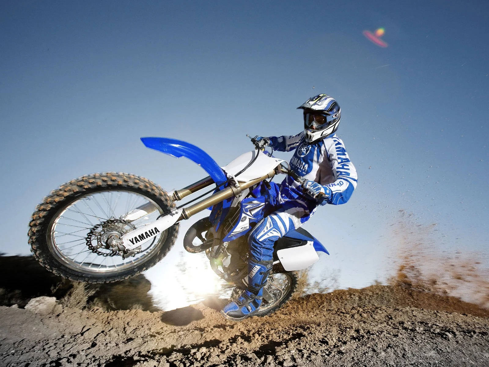 A Man Riding A Blue Dirt Bike On A Dirt Track Wallpaper