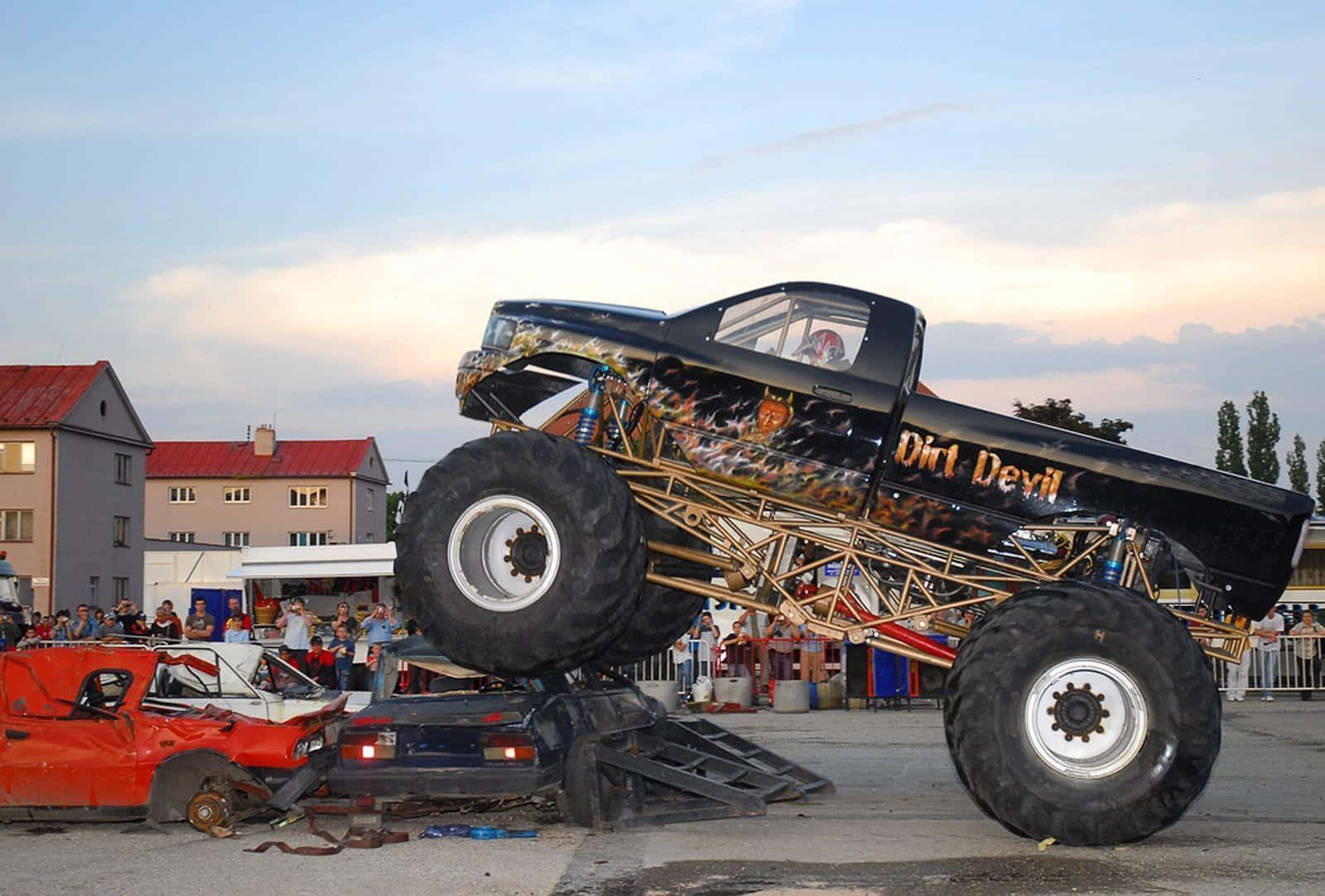 A Large Monster Truck Is On Top Of A Car