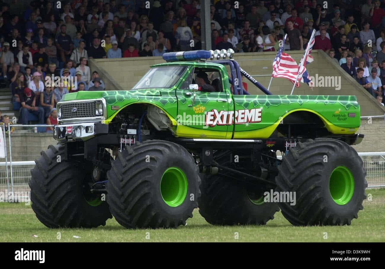A Green Monster Truck Driving Down The Track At A Show - Stock Image