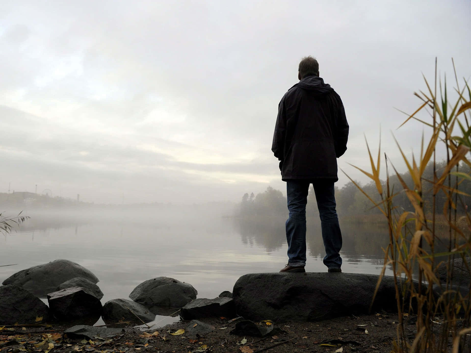 A Man Standing On Rocks Near A Lake