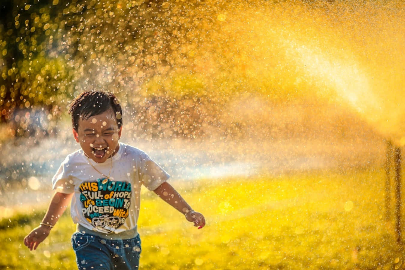 A Boy Running Through A Sprinkler