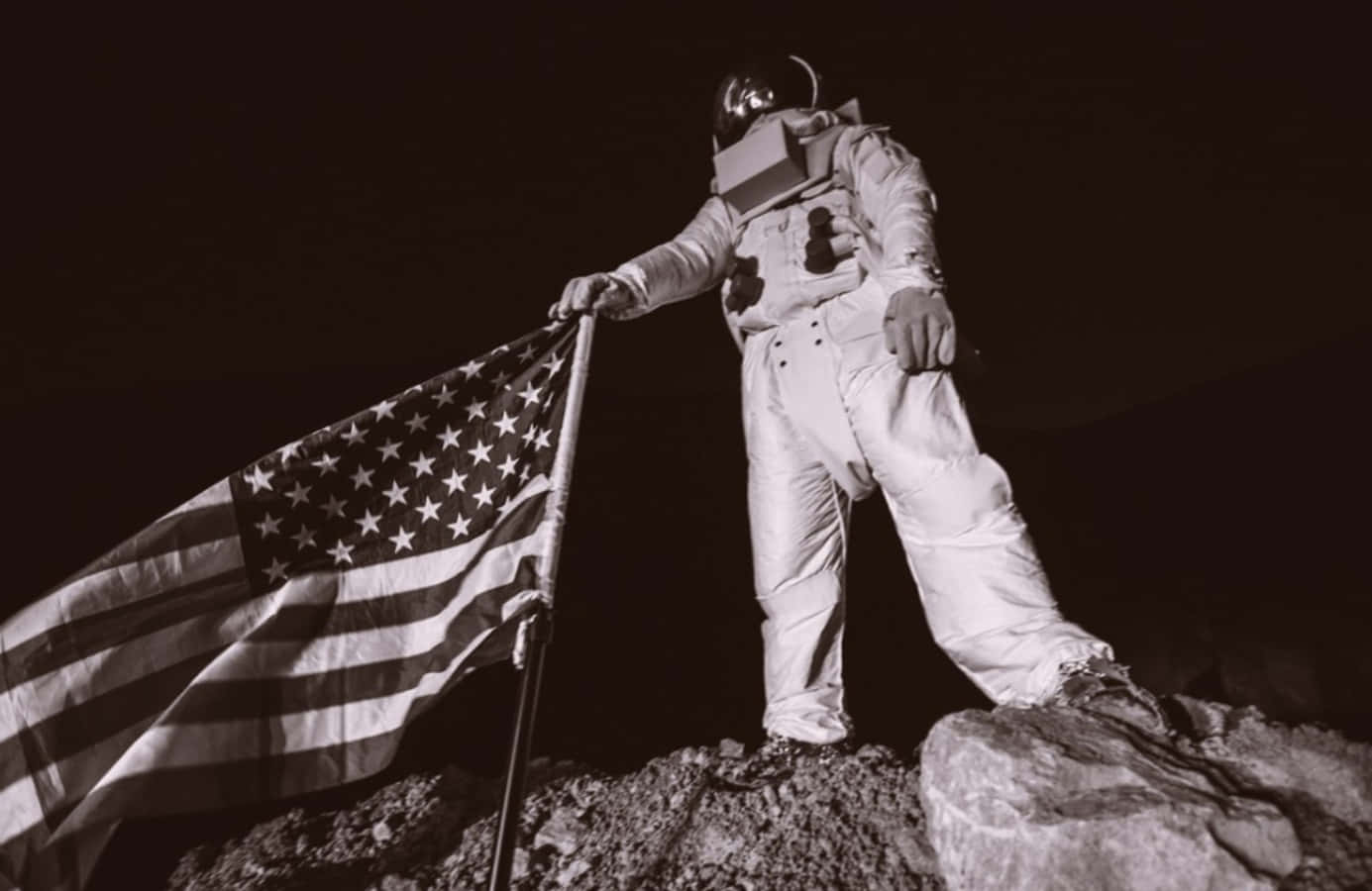 Astronaut Holding An American Flag On Top Of A Rock