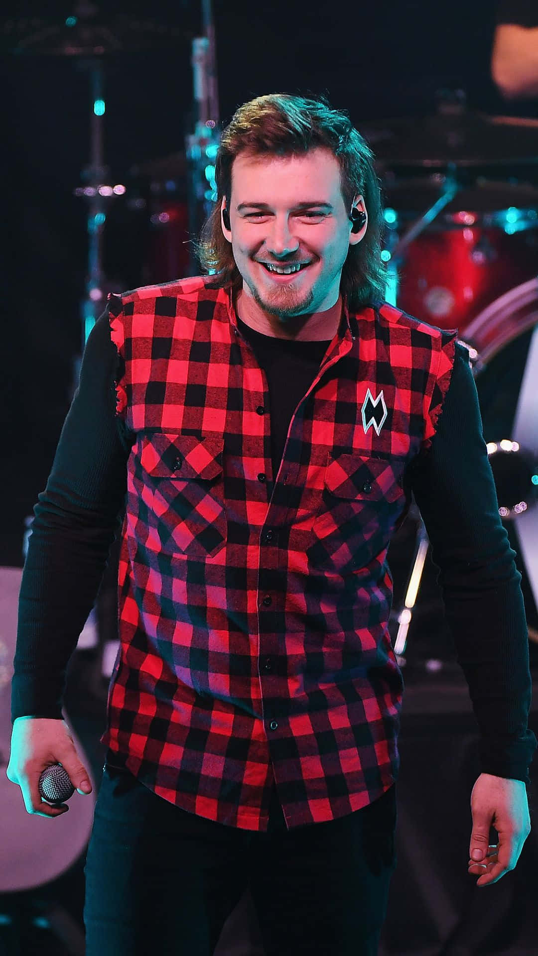 A Man In A Red And Black Plaid Shirt Is Smiling