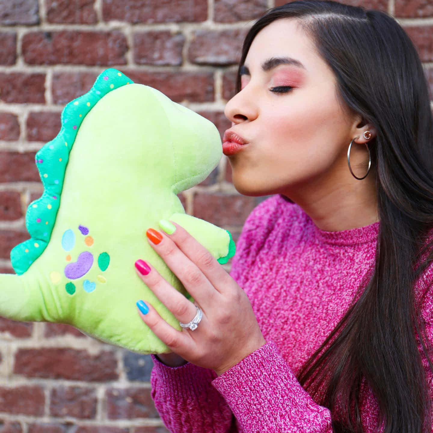 En kvinde kysser et grønt dino-plushdyr. Wallpaper