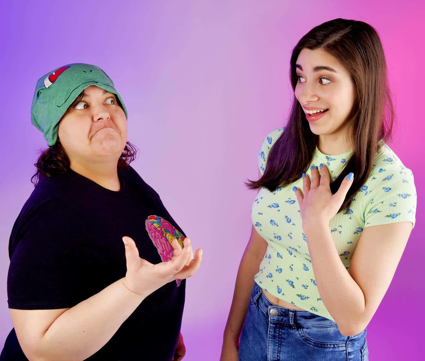 Two Women Standing Next To Each Other With A Pink Background Wallpaper