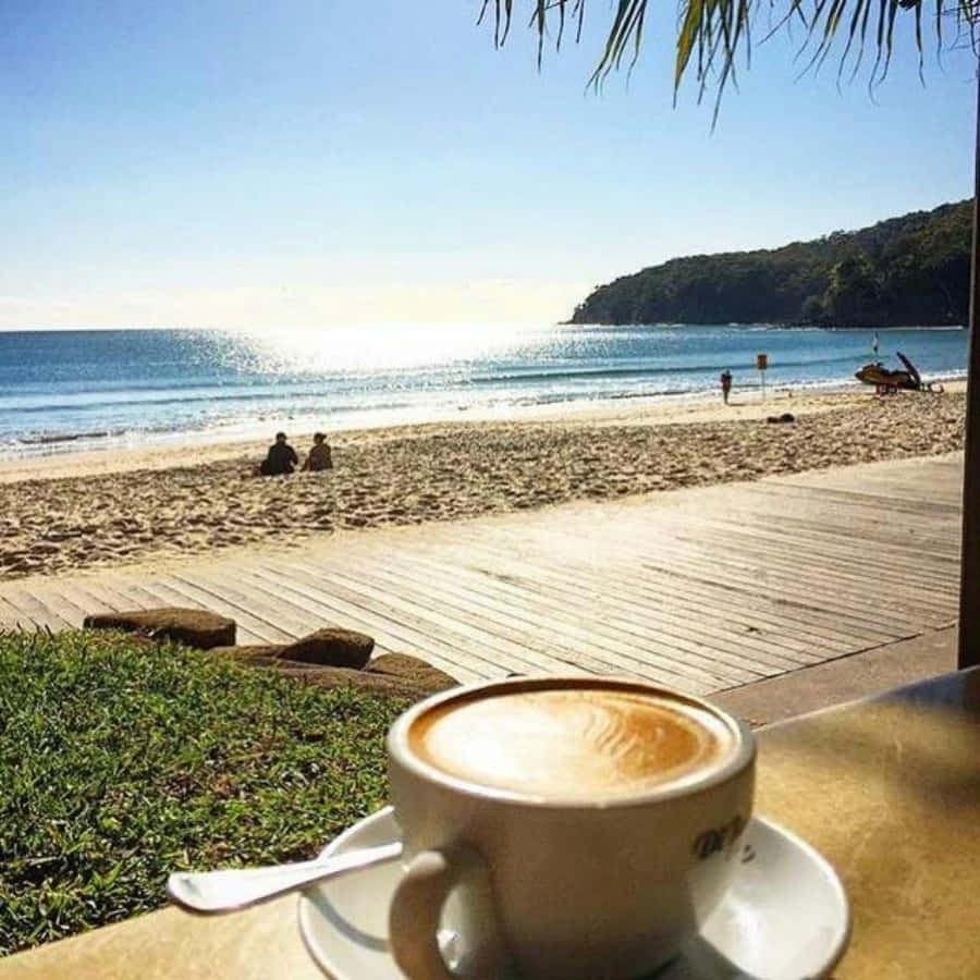 A Cup Of Coffee On A Table Overlooking The Beach