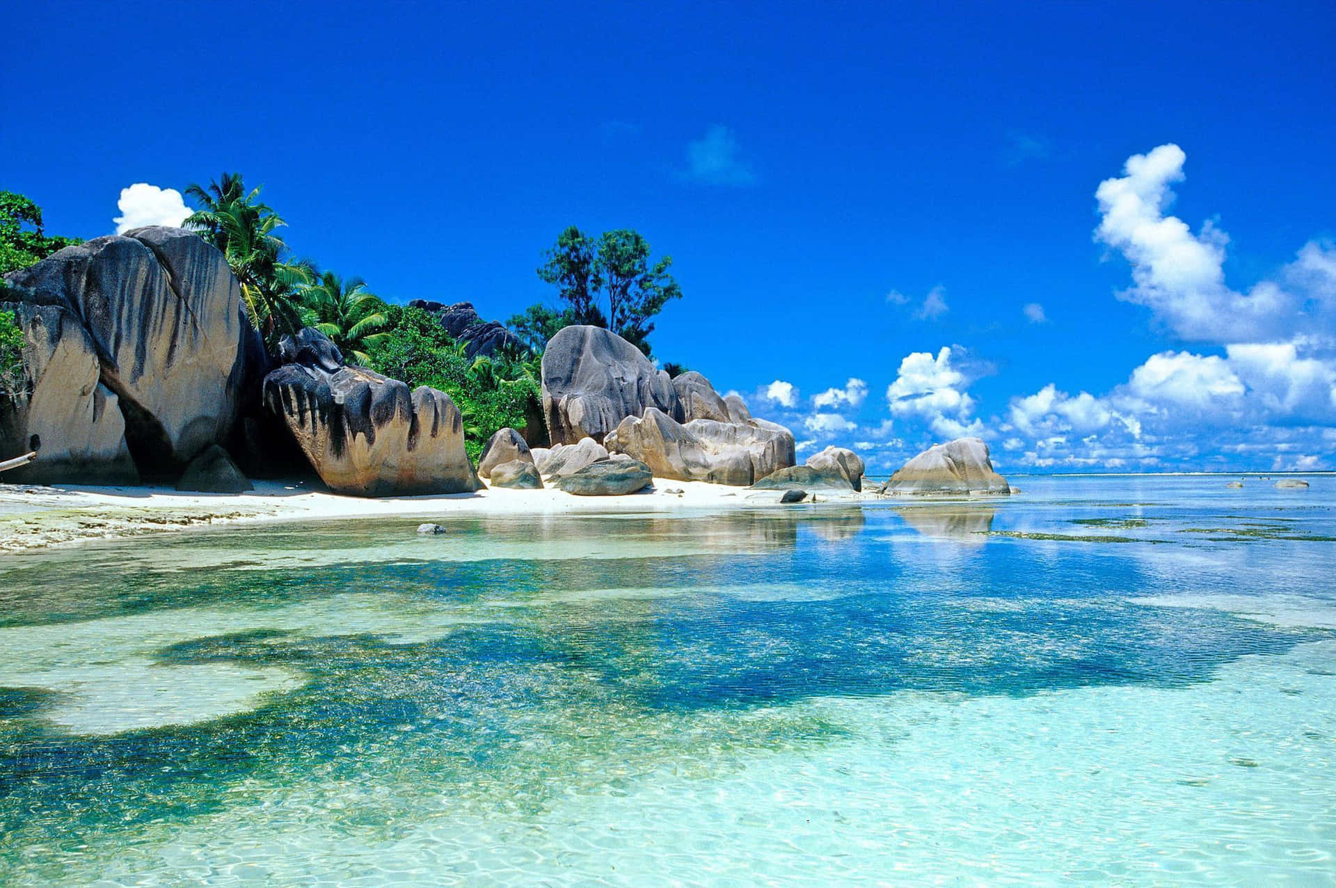 A Beach With Clear Water And Rocks Wallpaper