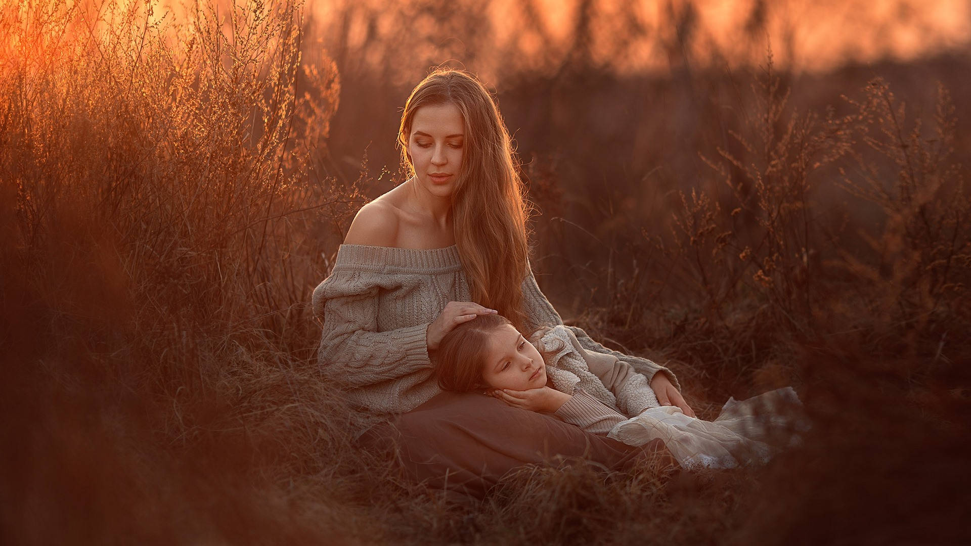 Mother And Daughter Resting On A Field Wallpaper