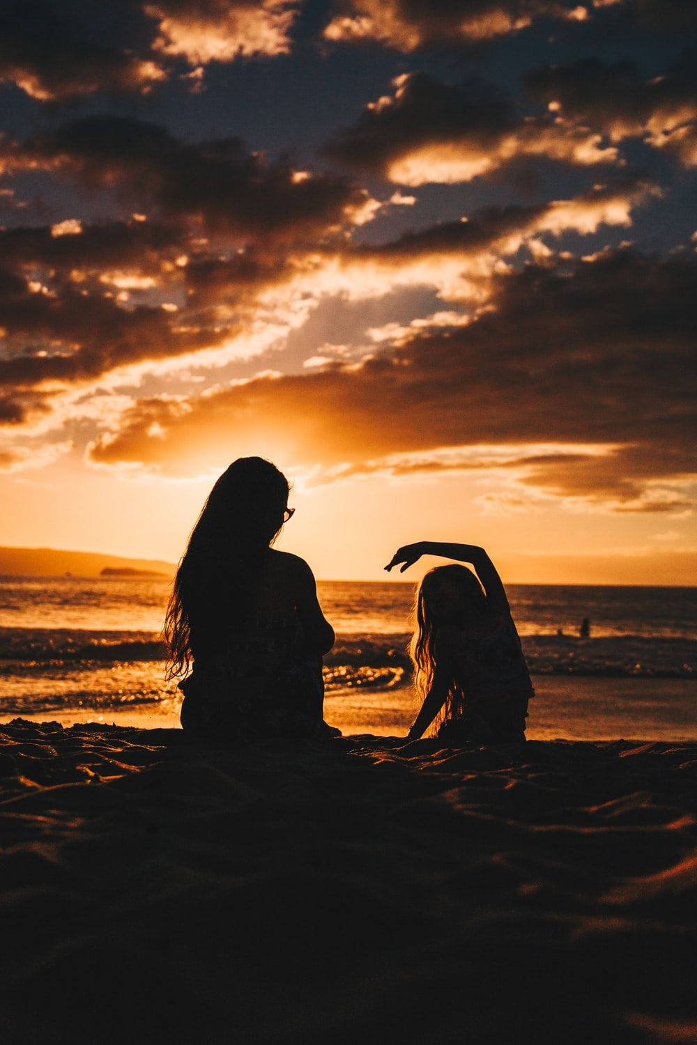 Madree Hija Observando La Puesta De Sol En La Playa Fondo de pantalla