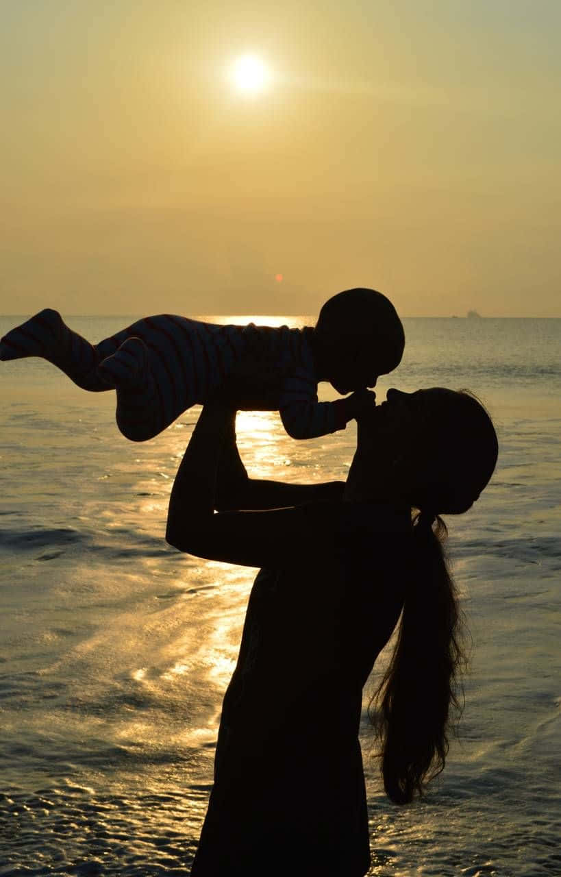 A Woman Holding Her Child At Sunset