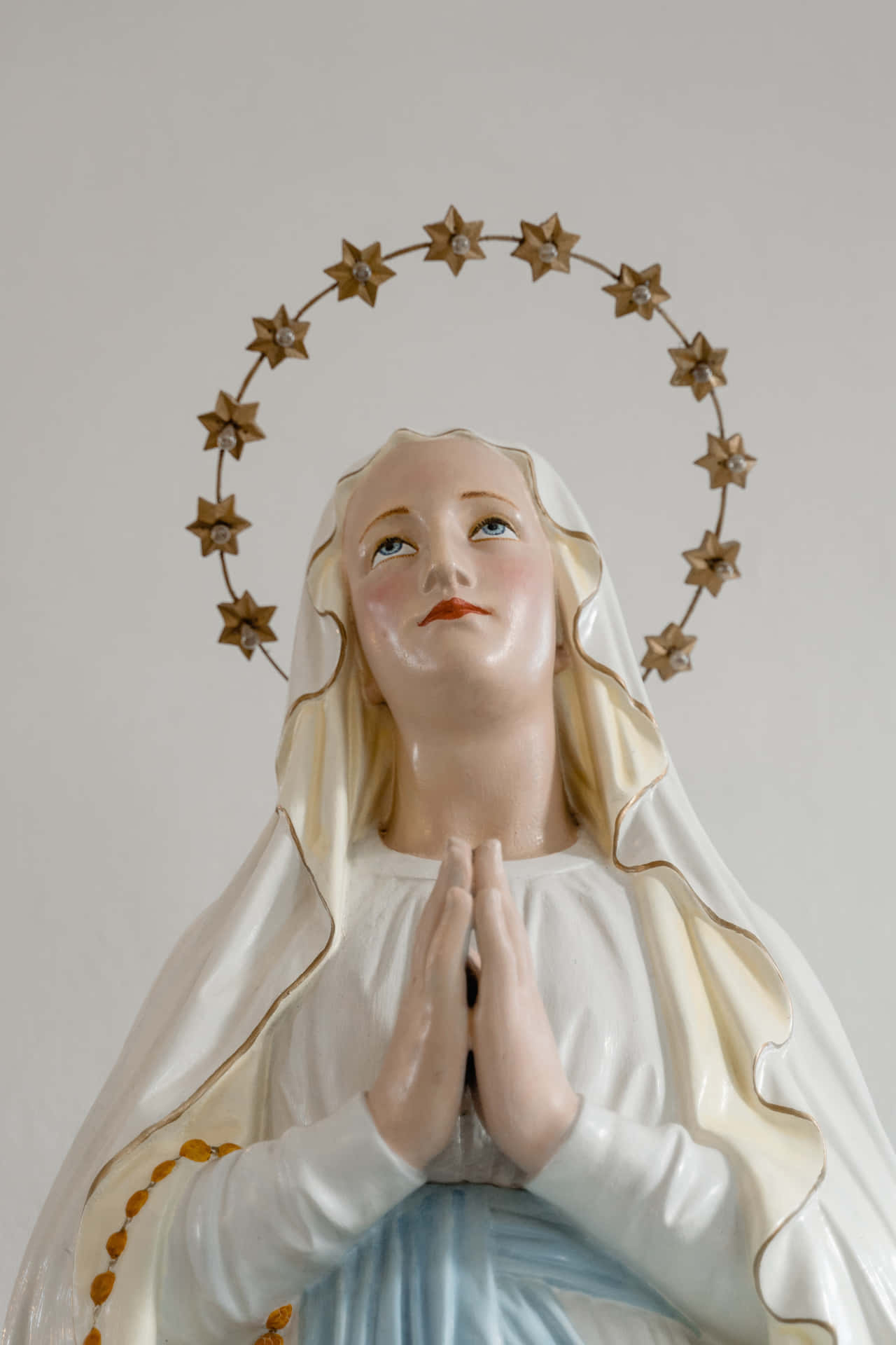 A Statue Of Mary Praying With Stars