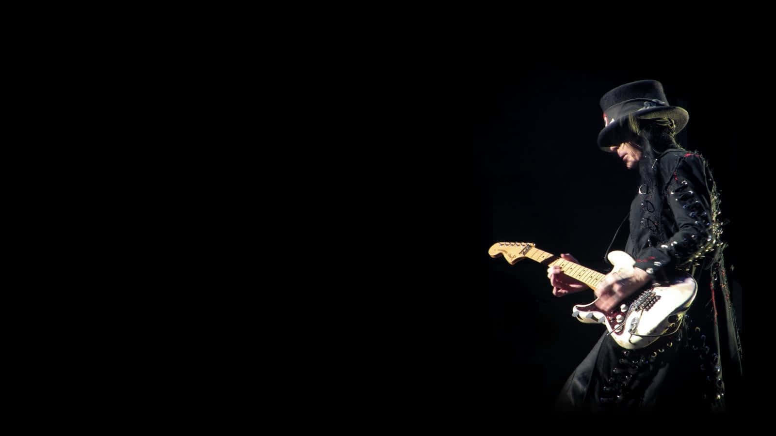 En mand i en sort hat, der spiller en elektrisk guitar. Wallpaper