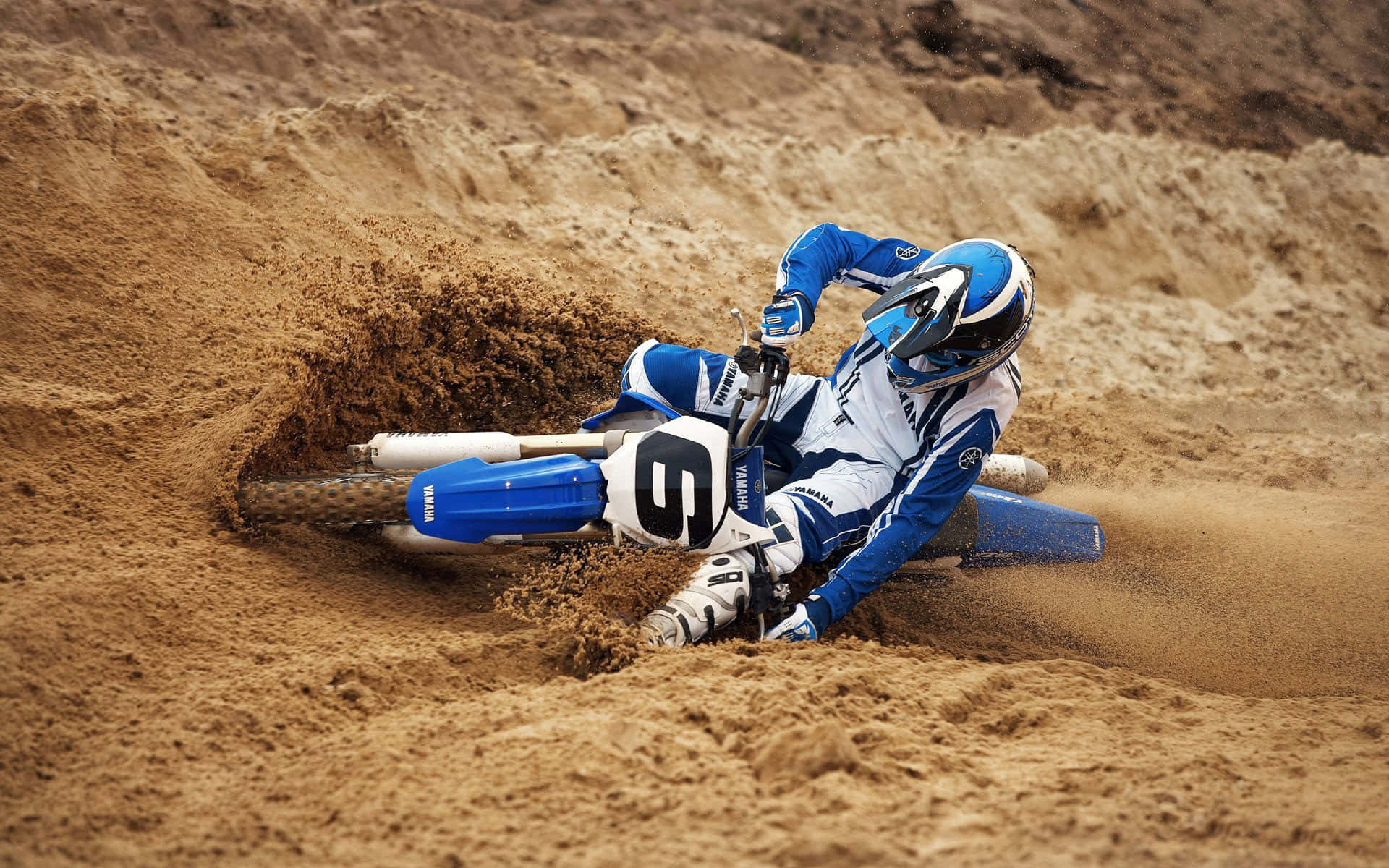 Pilote De Motocross Prend Un Virage Dans Le Sable Fond d'écran