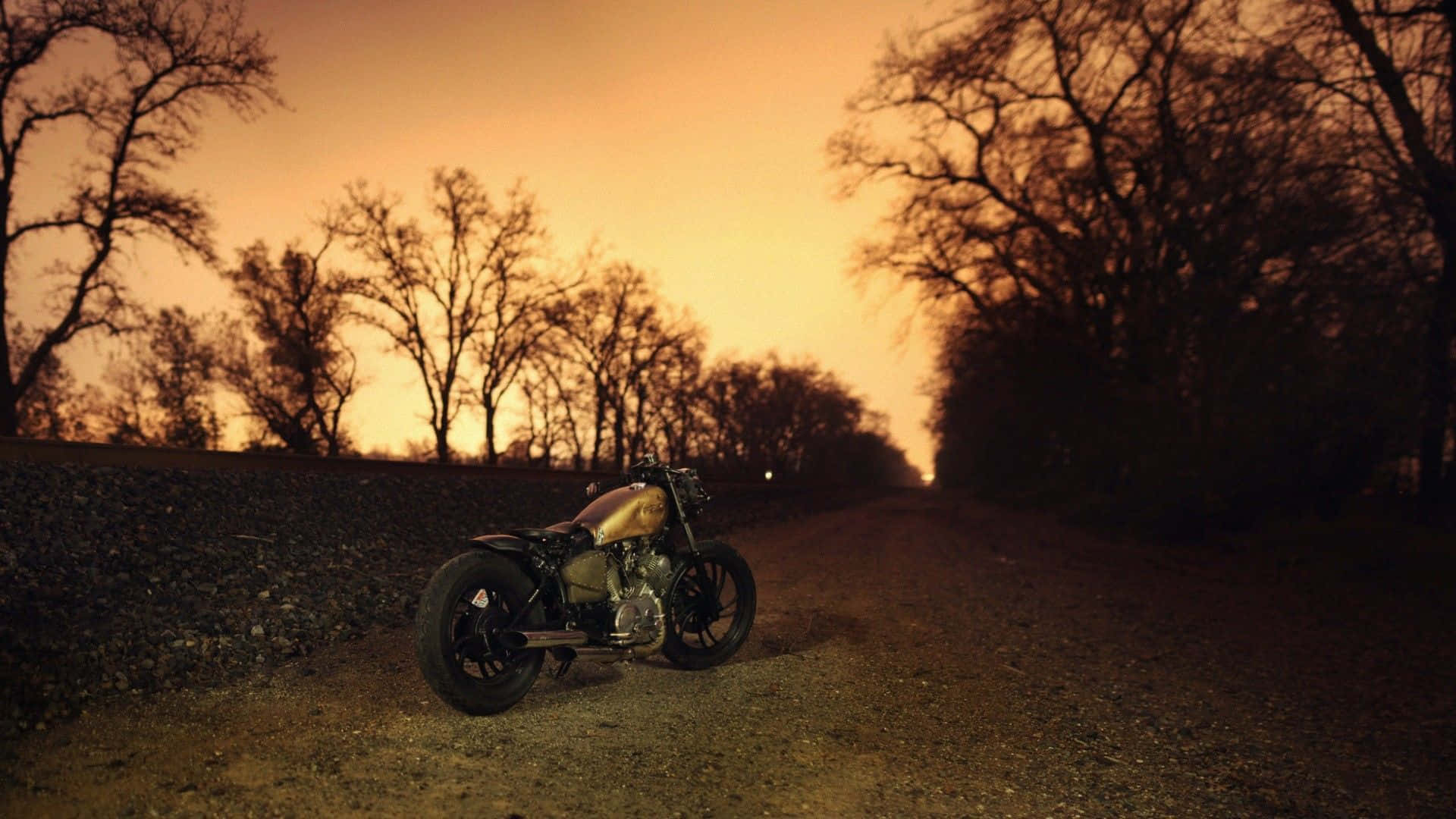 En motorcykel parkeret på en grusvej ved solnedgang